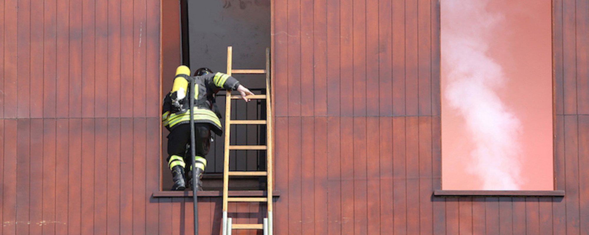firefighter with a long ladder with the mask and the oxygen cylinder while entering the building on fire